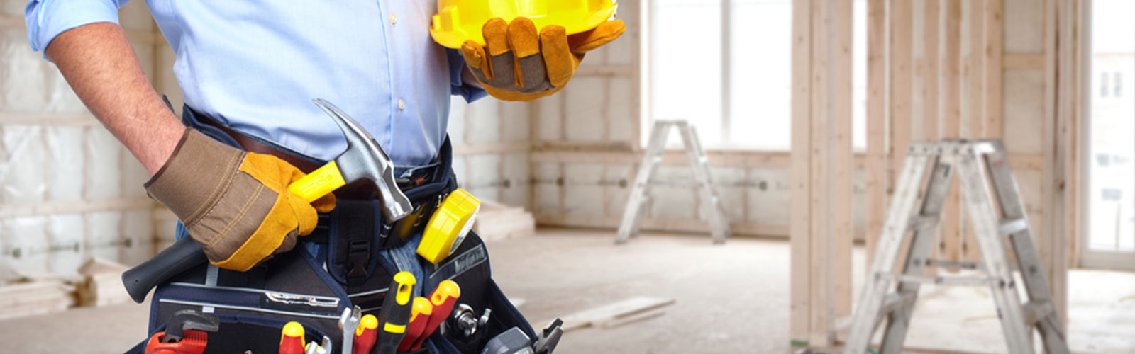 Bauarbeiter auf einer Baustelle mit gelbem Helm in der Hand